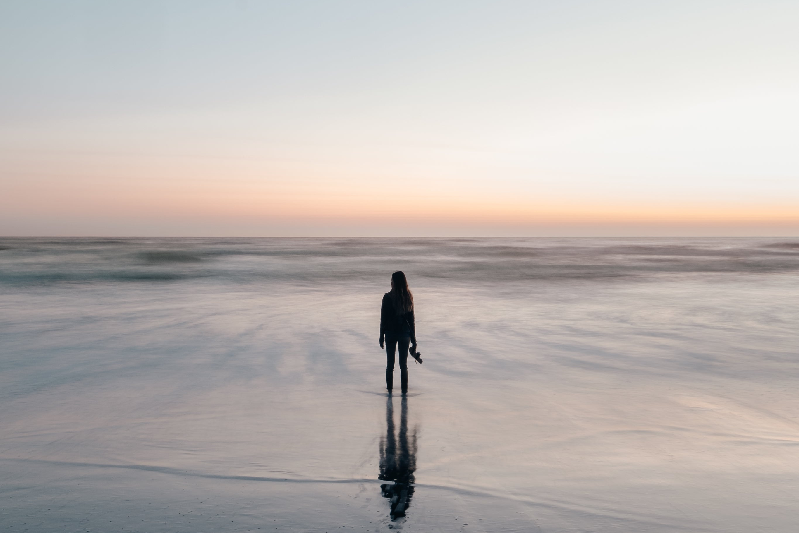 Person standing on a frozen lake at sunset